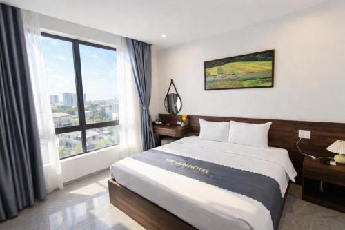 a bedroom with a large bed and a large window at The Sun Hotel - Ninh Bình in Kỳ Vĩ