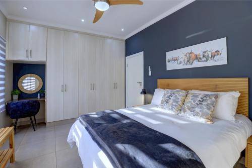 a bedroom with a large bed and a blue wall at Albatross @ Kingswood in George