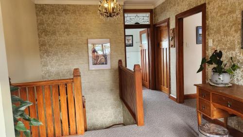 a hallway with a wooden staircase and a chandelier at La Casa in Napier