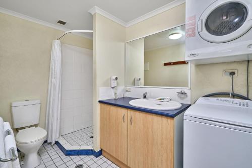 a bathroom with a sink and a washing machine at Trinity Beach Club Holiday Apartments in Trinity Beach