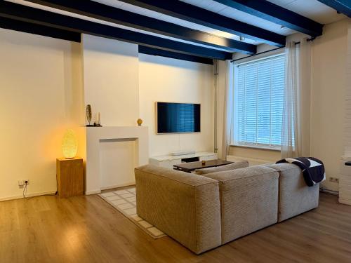 a living room with a couch and a tv at Perfectly located home between Den Bosch & Vught in Vught