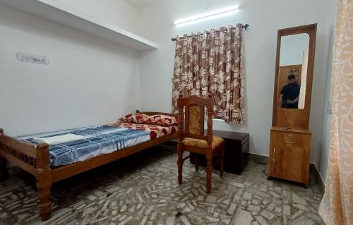 a bedroom with a bed and a chair and a mirror at Sandy Steps in Varkala