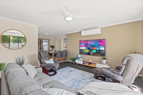 a living room with a couch and chairs and a flat screen tv at Family-Friendly 3 Bedroom Home in Hervey Bay in Pialba