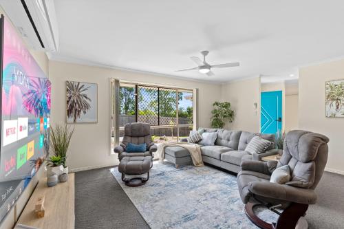 a living room with a couch and chairs and a tv at Family-Friendly 3 Bedroom Home in Hervey Bay in Pialba