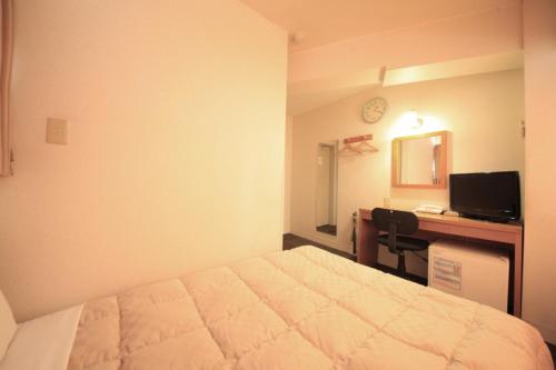 1 dormitorio con 1 cama y escritorio con ordenador en Hotel Musashino no Mori en Fuchu