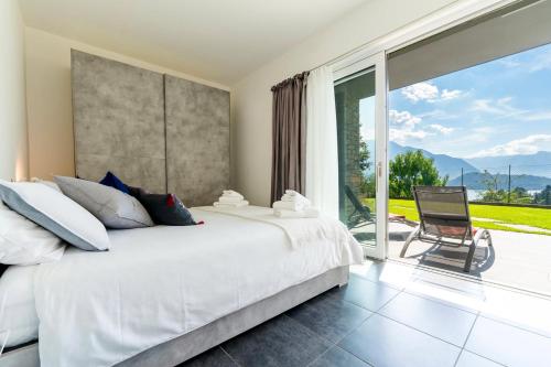 een slaapkamer met een wit bed en een groot raam bij La Filanda di Viano in Villa in Tremezzo