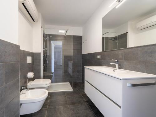 een badkamer met 2 wastafels, een toilet en een spiegel bij La Filanda di Viano in Villa in Tremezzo