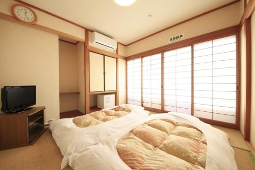 a bedroom with a large bed and a tv at Hotel Musashino no Mori in Fuchu