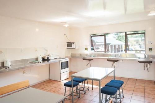 a kitchen with a table and blue chairs in it at Hanmer Springs TOP 10 Holiday Park in Hanmer Springs