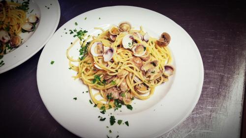 a white plate of pasta with mushrooms and onions at Hotel Gala in Pesaro