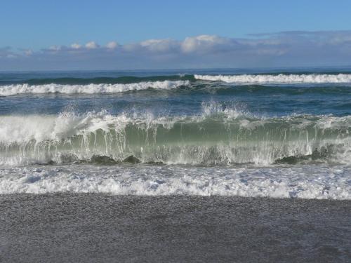 a group of waves in the ocean on a beach at Molyneux House in Kaka Point