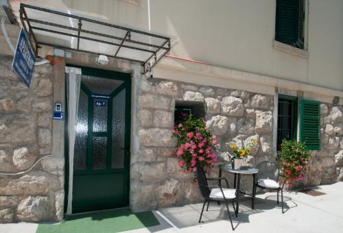 a stone building with a table and chairs and a door at Apartment Tomic A-5 in Lovran