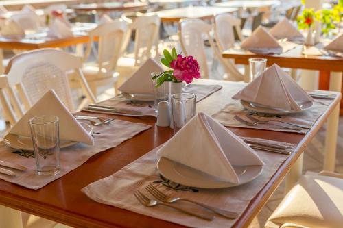 a table with plates and napkins and a flower on it at Rethymno Mare & Water Park in Rethymno Town
