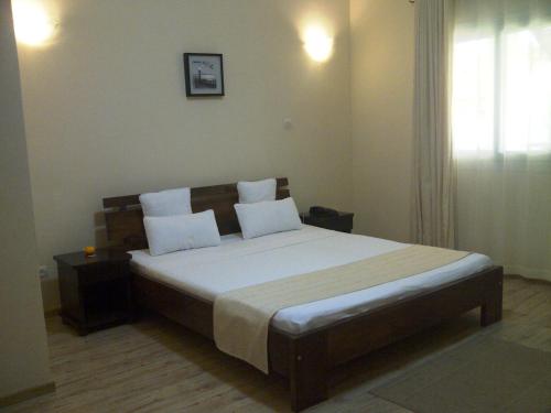 sypialnia z dużym łóżkiem z białą pościelą i poduszkami w obiekcie Hotel H1 Antsirabe w mieście Antsirabe