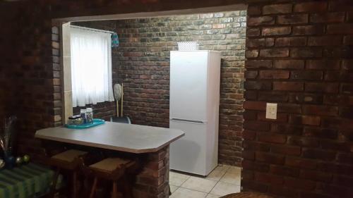 a kitchen with a white refrigerator in a brick wall at Do Drop In in Hoedspruit