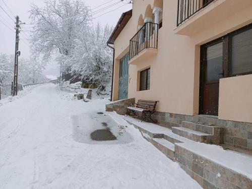 una strada coperta di neve con una panchina accanto a un edificio di Casa Tâmplarului a Giuleşti