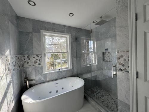 a white bath tub in a bathroom with a window at Serene waterfront getaway in Mashpee