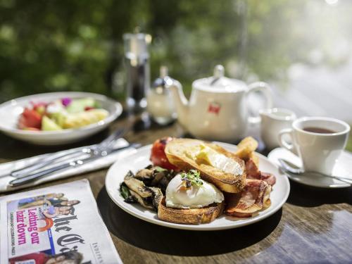 a table with a plate of breakfast food and coffee at Novotel Canberra in Canberra
