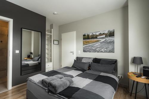 a bedroom with a black and white bed and a mirror at NürbLife Hotel in Nürburg