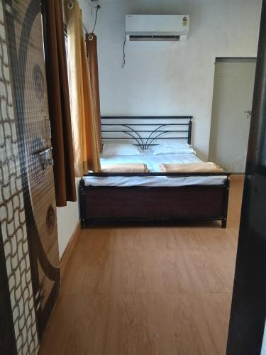 a bedroom with a bed and a wooden floor at Golden Oriole Homestay in Srīvardhan