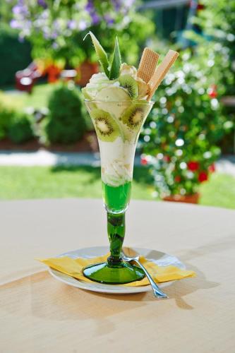 a green glass vase with ice cream on a plate at Gourmet-Hotel Grünwald in Leogang