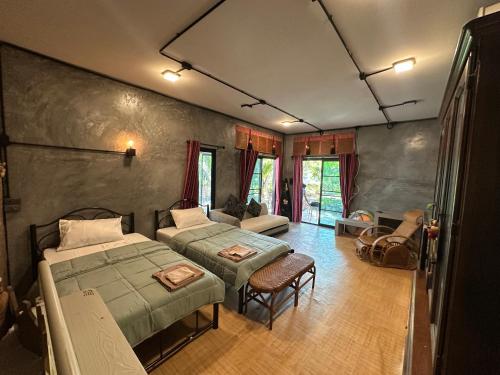 a bedroom with two beds and a couch at Ban Buarawong บ้านบัวระวงค์ in Ban Nong Faek