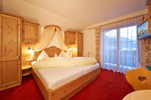 a bedroom with a bed and a large window at Gourmet-Hotel Grünwald in Leogang