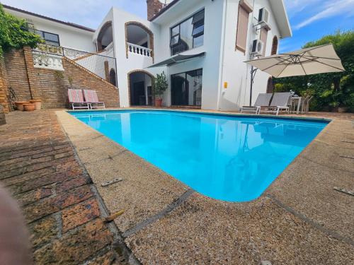 a swimming pool in front of a house at 5 Rembrandt Guesthouse in Somerset West