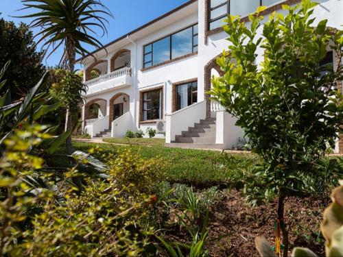 a white house with a palm tree in front of it at 5 Rembrandt Guesthouse in Somerset West