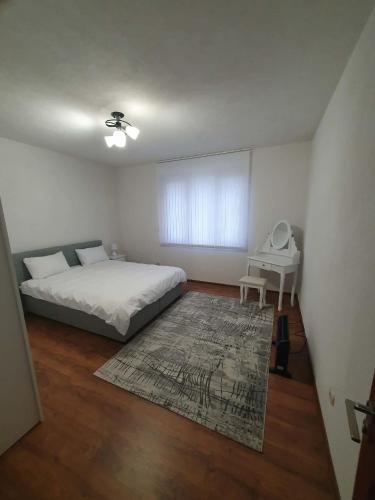 a white bedroom with a bed and a table at Levkov in Petrich