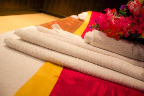 a pile of towels sitting on a table with flowers at Royal Phoenicia Hotel in Manama