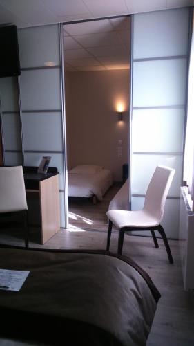 a bedroom with a white chair and a mirror at Hôtel Le Bayeux in Bayeux