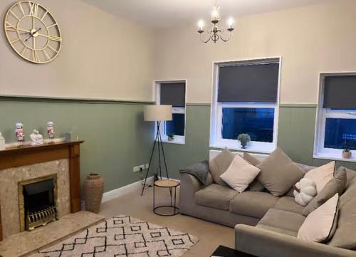 a living room with a couch and a clock on the wall at Beautiful Countryside Cottage Alnwick in Alnwick