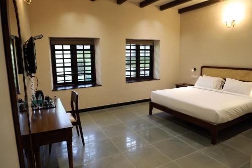 een slaapkamer met een bed, een bureau en ramen bij THE SUNSET BAY in Fort Kochi