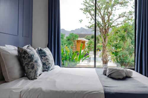 a white bed with pillows and a large window at Zana Villas in Krabi