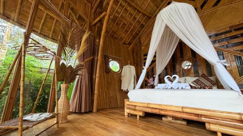a bedroom with a bed with a canopy at Wana Bamboo House by ecobreeze in Sidemen