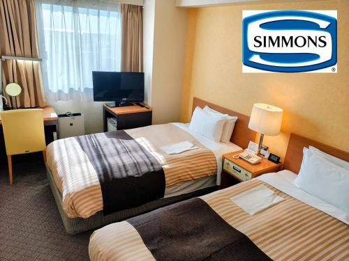 una camera d'albergo con due letti e una televisione di Grand Hotel Kanachu Hiratsuka a Hiratsuka