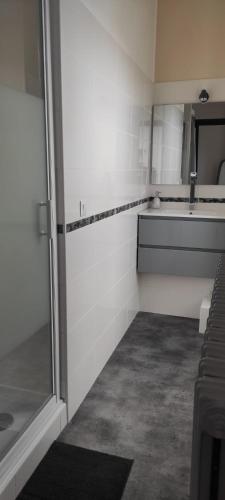 une salle de bains avec douche et murs carrelés blancs dans l'établissement Maison de vacances, au Guilvinec