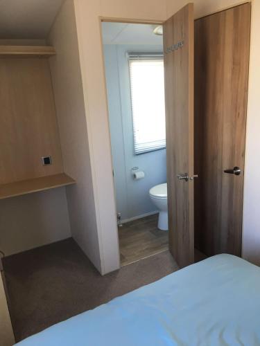 a room with a bed and a bathroom with a toilet at Lyons Robin Hood Rhyl North wales six berth caravan choice of two available in Meliden