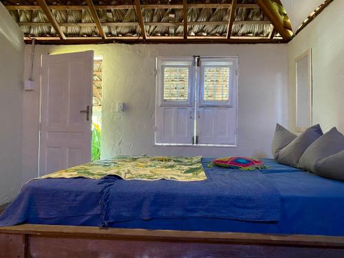 een slaapkamer met een blauw bed en een raam bij Casa Acquamarina in Atins