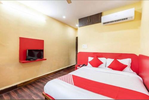 a bedroom with a red bed and a tv at Hotel Vanice Blue in Indore