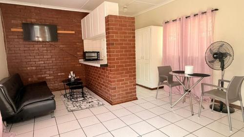 a living room with a brick wall and a table and chairs at Gaxela Space in Pietermaritzburg