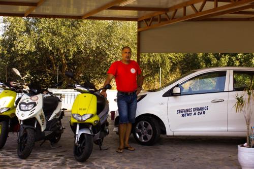 a man is standing next to two motor scooters at Studios by Climbing House in Panormos Kalymnos