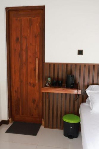 a bedroom with a door and a green stool next to a bed at Visit Wilpattu in Pahala Maragahawewa