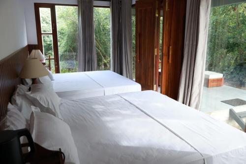 a bedroom with two white beds and a large window at Visit Wilpattu in Pahala Maragahawewa