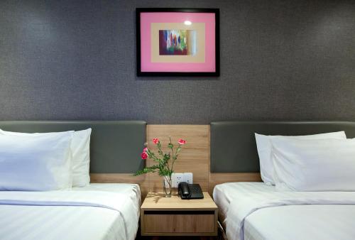 a hotel room with two beds and a table with flowers at Avanti Hotel in Ho Chi Minh City
