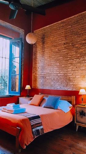 a bedroom with a large bed and a brick wall at Hostería Casa de Campo in Chascomús