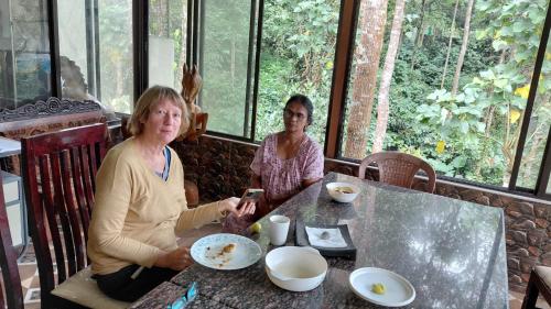 two women sitting at a table looking at a cell phone at Munnar Tree house and Farm in Munnar