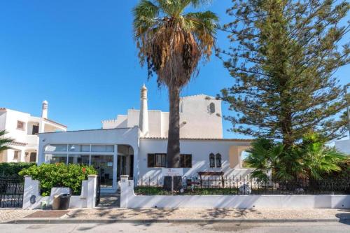 a white building with palm trees in front of it at Blife Sunya private rooms near airport and nature in Faro