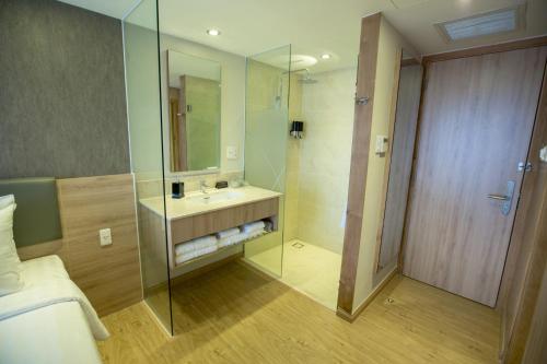 uma casa de banho com um lavatório e uma cabina de duche em vidro. em Avanti Hotel em Ho Chi Minh